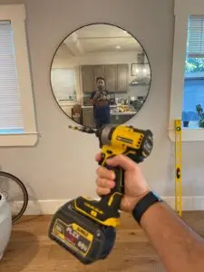 Person installing a custom floating shelf on a modern mirror room wall