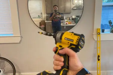 Person installing a custom floating shelf on a modern mirror room wall